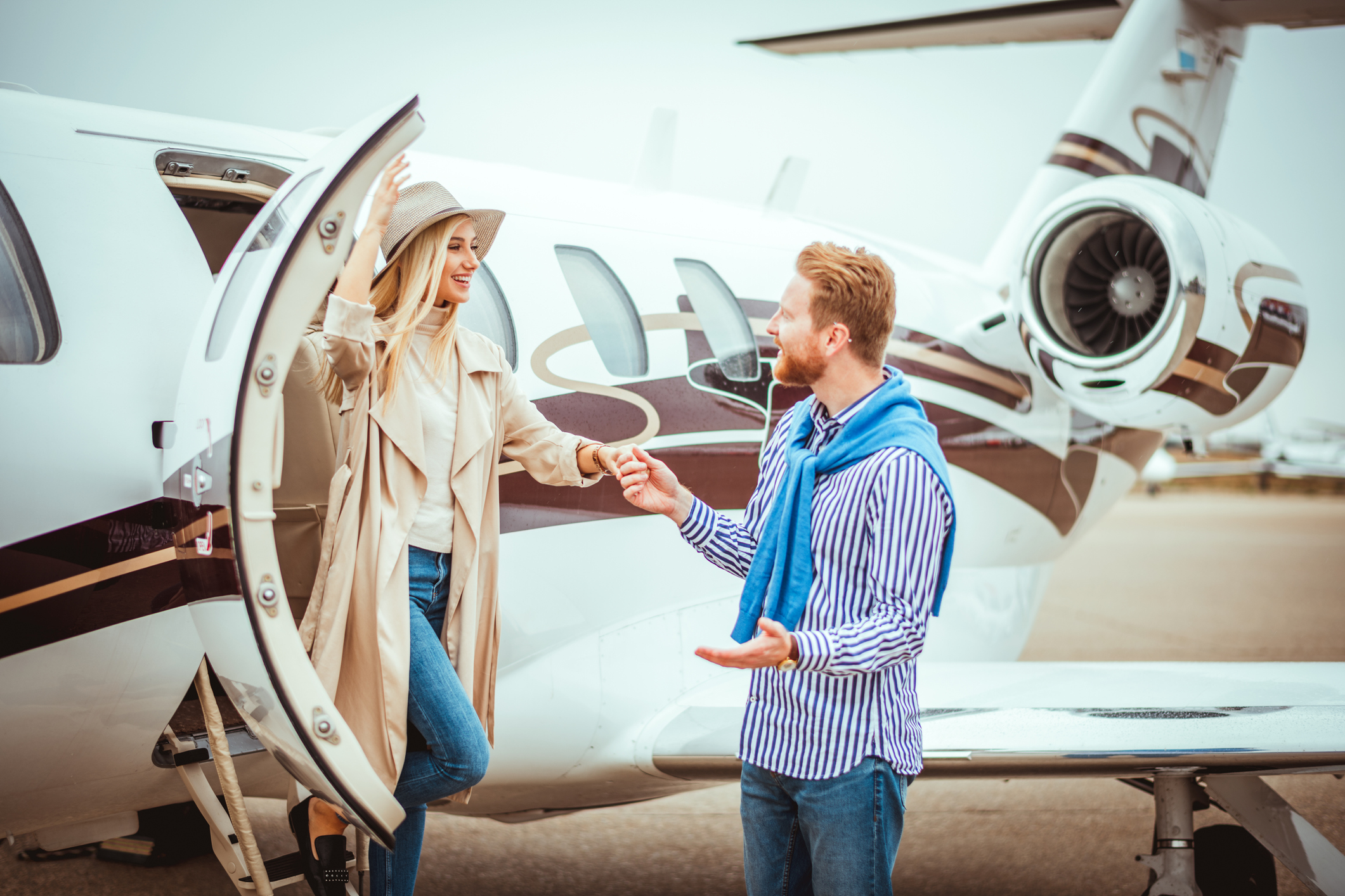 Young couple getting together in front of a private jet